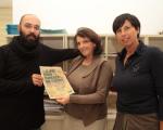 Al centro la presidente della Provincia di Rovigo, dott.ssa Tiziana Michela Virgili, mostra la locandina dell'iniziativa, insieme a due archivisti.